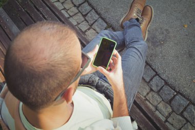 tahta bankta oturan ve smartphone açık, en iyi görünümü'nü kullanarak adam 