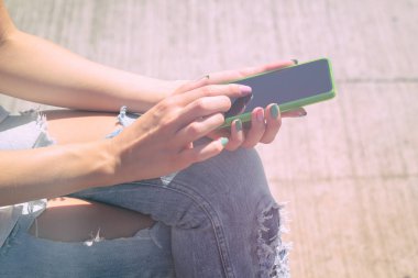 ahşap arka plan üzerinde otururken Smartphone kullanan kadın 