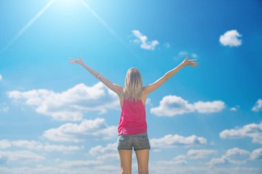 Arkadan Görünüş kadının kabarık bulutlar ile mavi gökyüzü karşı ayakta kaldırdı elleriyle 