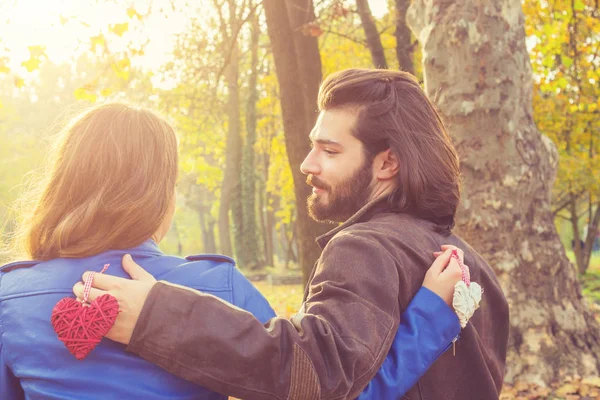 El sonbahar orman kadında kucaklayan kırmızı dekoratif kalbi olan yakışıklı adam 
