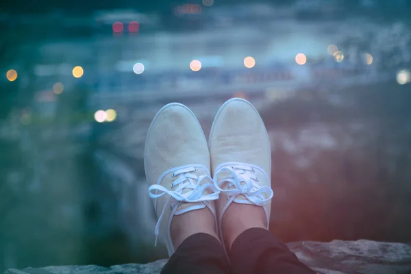 Man\'s shoes with distant city scape in twilight / dusk.