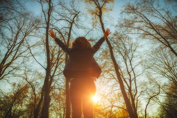 日出时妇女站在森林里伸出双臂的背观 — 图库照片