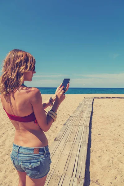 Açık havada akıllı telefon kullanan genç bir kadın.