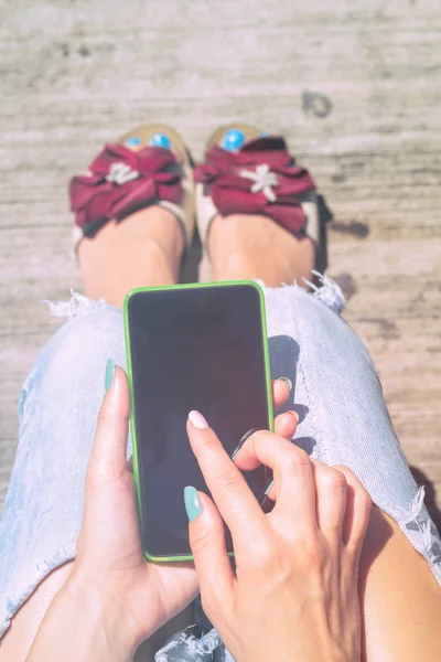 ahşap arka plan üzerinde otururken Smartphone kullanan kadın 