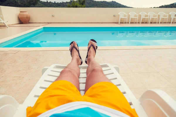 Man sunbathing on the sandy beach. Shallow depth of field on feet and flip flops