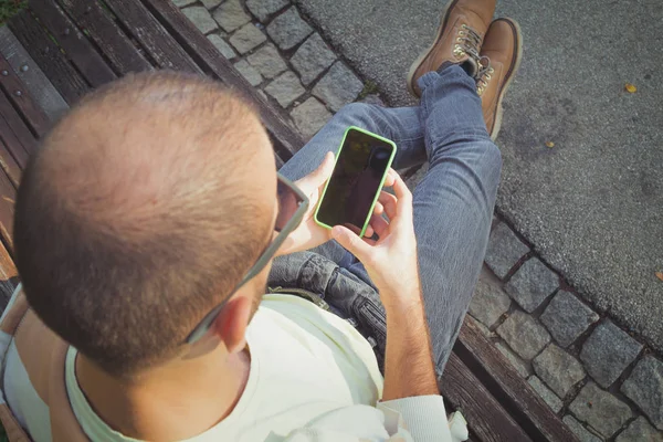 tahta bankta oturan ve smartphone açık, en iyi görünümü'nü kullanarak adam 