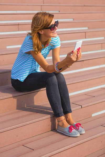 kahverengi merdivenlerde oturan ve smartphone kullanarak kadın