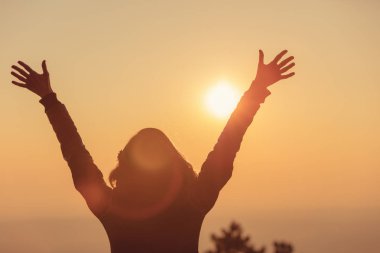 arkadan görünüşü karşı bulanık gökyüzü günbatımı uzanmış kollarıyla duran kadın 