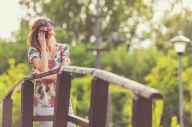 Kadın akıllı Park ahşap köprü üzerinde dururken söz