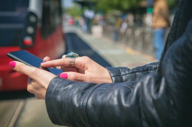 Smartphone duran tramvay istasyonunda kullanan kadın