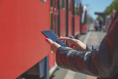 Smartphone trenin yanında dururken istasyonunda kullanan kadın 