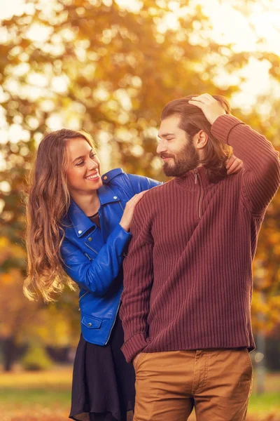 smiling gorgeous woman hugging happy handsome man with blurred autumn forest on background
