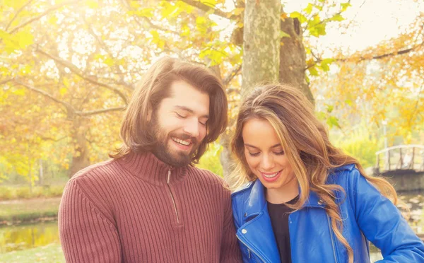 微笑华丽的女人和英俊的男人看着下来 而在秋天的森林里站在一起 — 图库照片