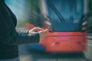 Smartphone duran tramvay istasyonunda kullanan kadın