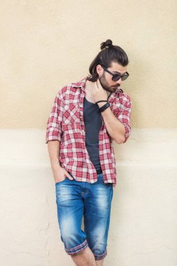 saç modeli güneş gözlüğü ve trendy kıyafetler bej duvar arka plan üzerinde poz ile yakışıklı adam 