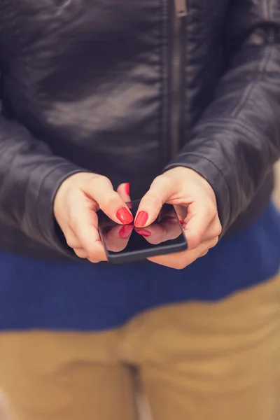 赤で女性の手マニキュア屋外 クローズ アップのスマート フォンの入力メッセージ — ストック写真