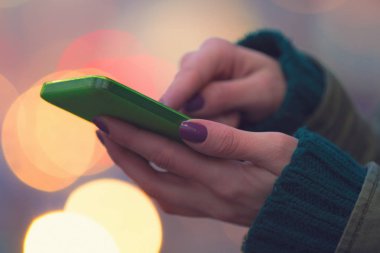 Mor manikür yeşil smartphone, yakın çekim kullanarak ile eller 