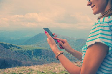 arka plan üzerinde Dağları ile tepede duran Smartphone kullanan kadın 