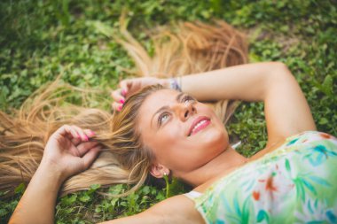 Genç güzel kız parkta çim üzerinde yalan