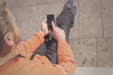 Smartphone açık, en iyi görünümü'yazarak giyen turuncu kazak dostum 