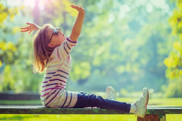 Kleines Mädchen Sitzt Bei Sonnigem Wetter Mit Erhobenen Händen Auf — Stockfoto