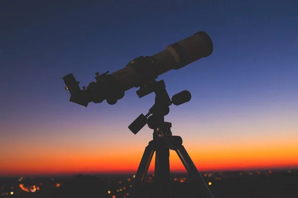 Silhouette of a telescope with stars on the sky