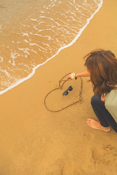 海の砂にハートを描く少女 海のビーチ — ストック写真