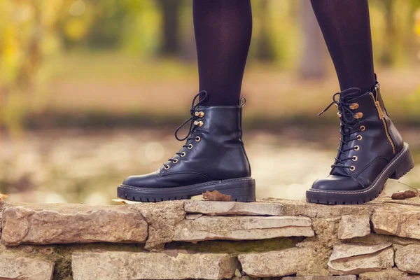 Frauenbeine Stylischen Schwarzen Lederstiefeln Stehen Auf Steinzaun Mit Verschwommenem Herbstwald — Stockfoto