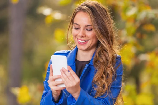 Mosolygó Kék Bőrkabát Használ Smartphone Háttér Életlen Őszi Erdő Gyönyörű — Stock Fotó