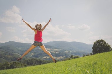 arkadan görünüşü kadın kaldırdı elleriyle yeşil çim güneşli gün atlama 