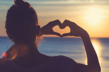 Kız plajda elleriyle kalp şekil verme