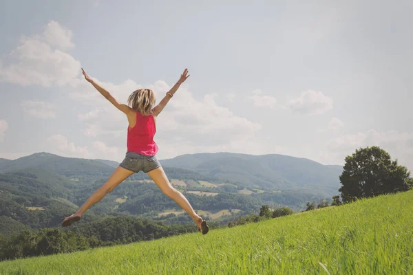 arkadan görünüşü kadın kaldırdı elleriyle yeşil çim güneşli gün atlama 