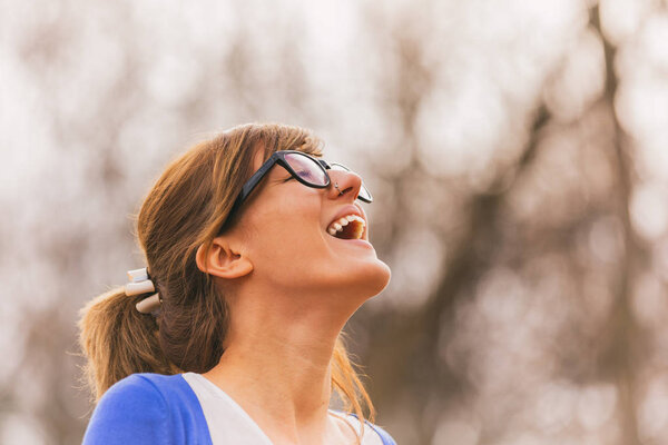 happy cute woman in eyeglasses smiling with closed eyes forest at sunny day