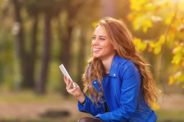 Mosolygó Kék Bőrkabát Gazdaság Smartphone Val Háttér Homályos Őszi Erdő — Stock Fotó