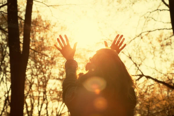 kadın ayakta ormanda güneş doğarken uzanmış kollarıyla