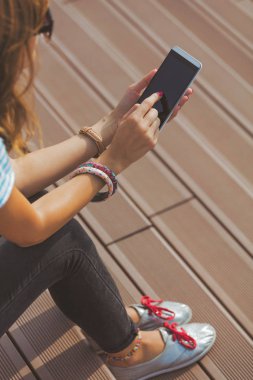 kahverengi merdivenlerde oturan ve smartphone kullanarak kadın