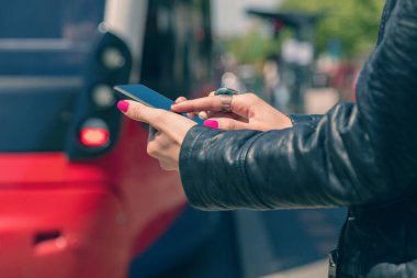 Smartphone duran tramvay istasyonunda kullanan kadın