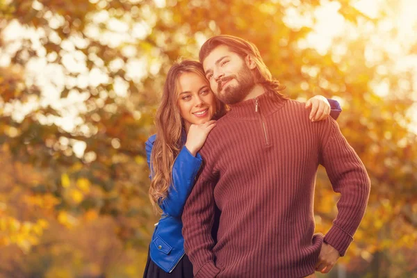 gülümseyen güzel kadın mutlu yakışıklı adam arka plan üzerinde bulanık sonbahar orman ile sarılma  