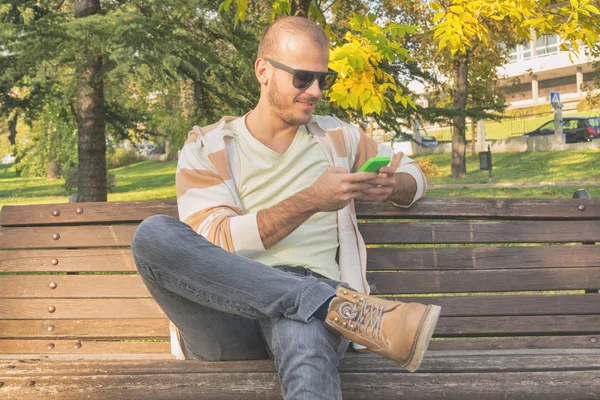 Hombre Usando Teléfono Inteligente Mientras Está Sentado Banco Madera Parque — Foto de Stock