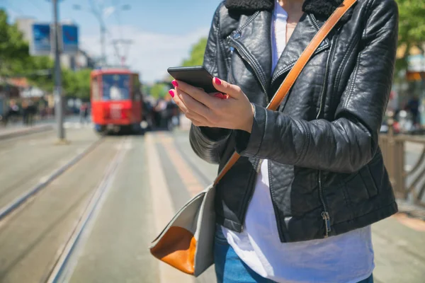 arka plan üzerinde bulanık tramvay ile smartphone istasyonda dururken yazarak eller  