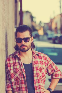 saç modeli güneş gözlüğü ve trendy kıyafetler bej duvar arka plan üzerinde poz ile yakışıklı adam 