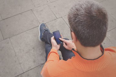 Smartphone açık, en iyi görünümü'yazarak giyen turuncu kazak dostum 