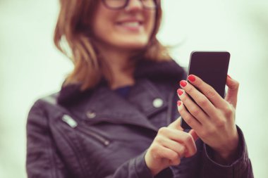 gözlük ve smartphone duran bulanık doğal zemin üzerine yazarak ceket giyen kadın 