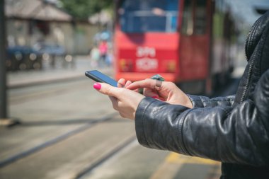 arka plan üzerinde bulanık tramvay ile smartphone istasyonda dururken yazarak eller  