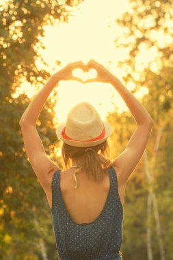 arkadan görünüşü kaldırdı elleriyle ayakta ve kalp işareti sonbahar ormanda gösterilen kadın 