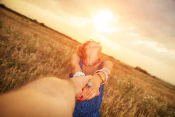 草原で夕暮れを楽しみながら男性の手を保持している女性 — ストック写真