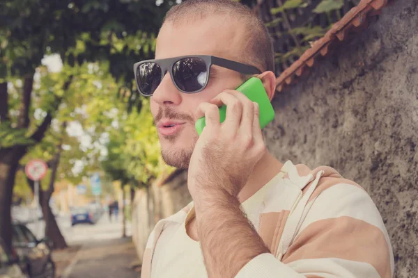 Hombre Sonriente Usando Teléfono Inteligente Mientras Apoya Pared Hormigón Calle —  Fotos de Stock