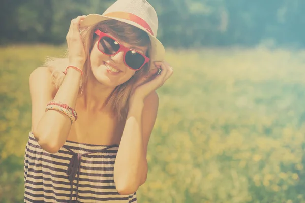 愉快的微笑的妇女在帽子和太阳镜在草甸享用 — 图库照片