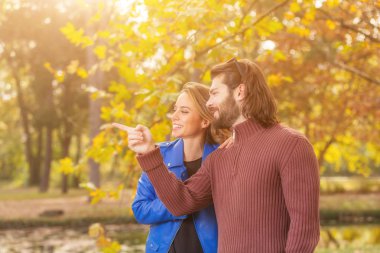 yakışıklı adam gülümseyen güzel kadın ve uzak sonbahar parkta işaret ile ayakta   