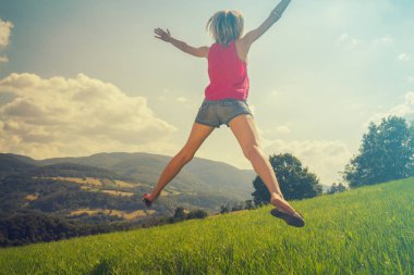 arkadan görünüşü kadın kaldırdı elleriyle yeşil çim güneşli gün atlama 
